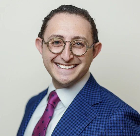Dr. Ariel Steinberger, DDS, in a blue jacket and magenta tie, smiling.