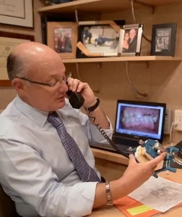 Dr. Allan Mohr at his desk, reviewing a smile on a laptop screen.
